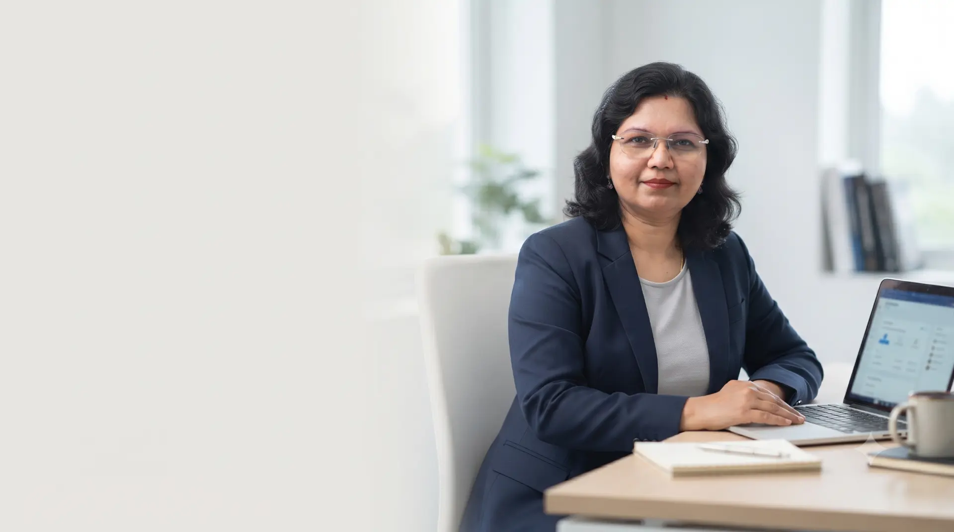 Deepti Nema, founder of QriusAI, seated at her desk with a laptop